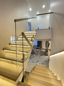 Стеклянное ограждение с деревянными перилами для лестницы в доме